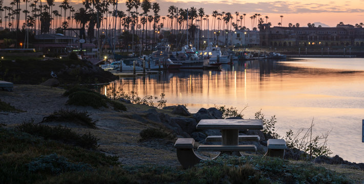 Marina Park Picnic Table Sits In Foreground View Of Reflective Water Of Ventura Harbor At Dawn.