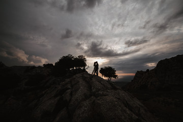 Fototapeta premium couple standing on the top of mountain, holding hands and watching sunset