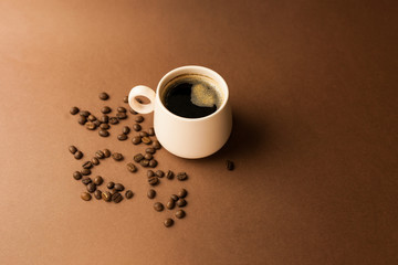 Cup of coffee with coffee beans on a brown background.