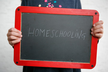 Child holding Chalkboard with Homeschooling Lettering
