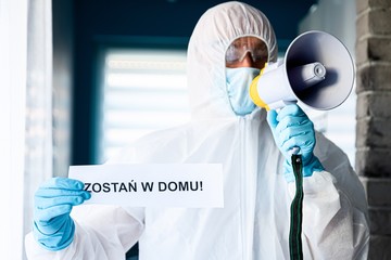 Fototapeta premium Medic holding card with message Stay at home in Polish language
