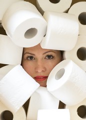 Close-up of beautiful woman surrounded by toilet paper. Hoarding toilet paper due to COVID-19 panic, home isolation, preparing for coronovirus quarantine