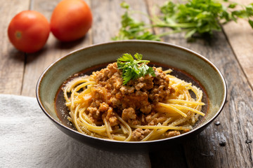 Spaghetti bolognese with parmesan cheese on wooden background