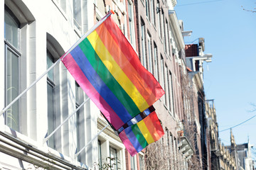 Rainbow LGBTQ Pride flag on the flagpole on the facade of the house