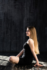 Fototapeta na wymiar Beautiful girl with long hair in black sportswear is engaged in morning yoga and sitting in Lotus position.