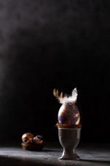 Golden egg. Easter gold egg wth feather above. Easter egg decoration with patina