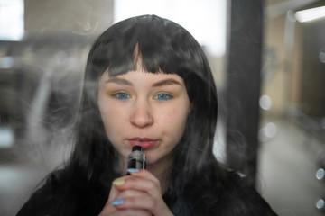 Vaping teenager. Young pretty white caucasian teenage brunette girl with blue eyes and problem skin...