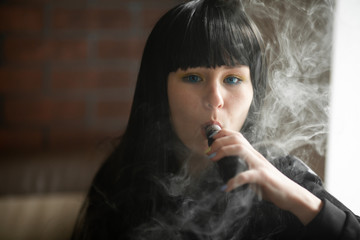 Vaping teenager. Young pretty white caucasian teenage brunette girl with blue eyes and problem skin...