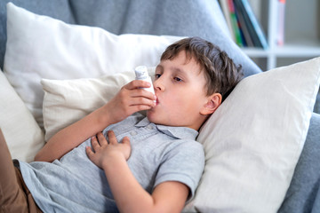 Obraz na płótnie Canvas Sick boy tired from chest coughing holding inhaler, having asthma using inhaler.