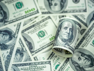 Roll of hundred dollar bill on dollar