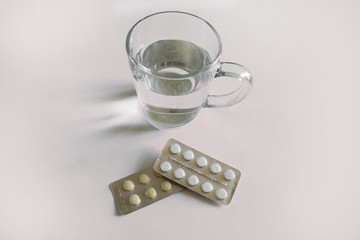 a glass of water and two packs of tablets