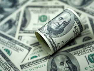 Roll of hundred dollar bill on dollar