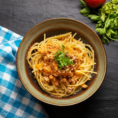 Spaghetti bolognese with parmesan cheese on dark background