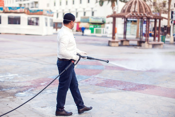 Man doing disinfection of street to protect against coronavirus