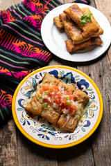 Mexican chimichanga with melted cheese and pico de gallo sauce on wooden background