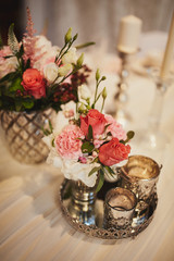 decoration of wedding table. White and pink flowers in vase and candle in silver candlesticks on the table. wedding day. selective focus