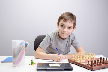 schoolboy studying homework math during his online lesson at home, social distance during quarantine, self-isolation, online education concept, home schooler, playing chess