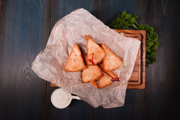 Appetizing fried cheese with sauce on a wooden tray. Studio photography of food in the cooking industry, dark background