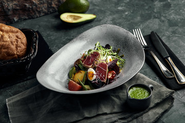 Nicoise salad with tuna on a gray plate, on a serving table. A beautiful dish from the chef, food photo, gray background, copy space, traditional French cuisine.