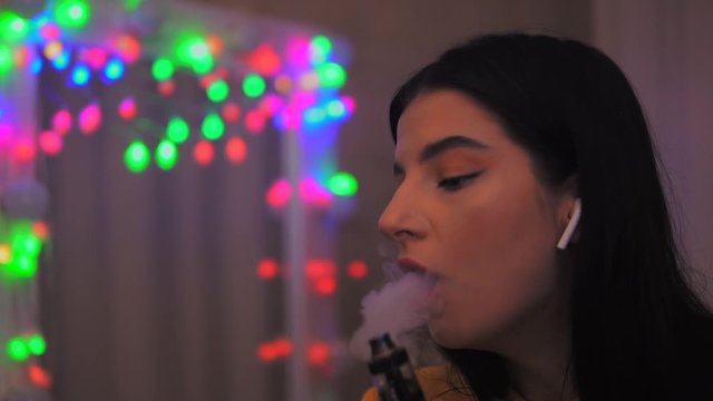 Close-up of beauty girl inhaling an e-cigarette vaping device. Slowm motion