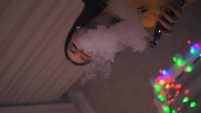 Young girl smokes vape, vaping, electronic sigarette slow motion vertical video