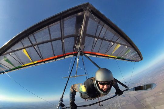 Hang glider pilot with his colorful wing flies high far away from other people.