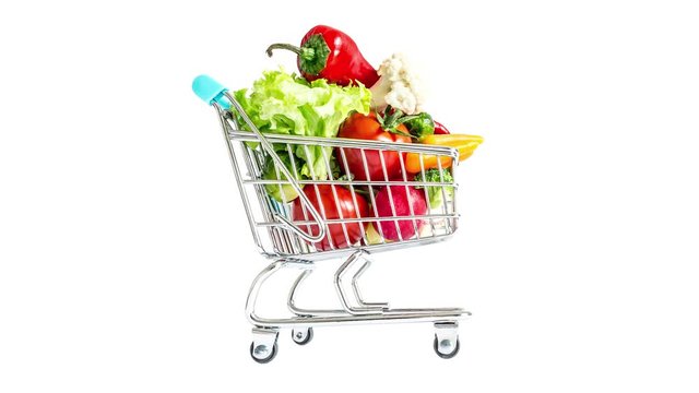 Shopping cart moving fast from side to side and quickly filling with vegetables and fruits. Mountain of fresh vegetables and fruits in a overcrowded trolley. Consumerism, sale and shopping concept.