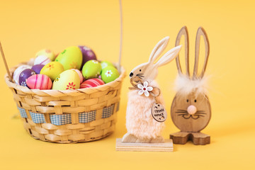 Wooden Easter Bunny with Easter eggs, on an isolated yellow background