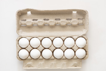 A dozen eggs in a carton isolated on white background