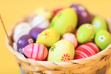 Fototapeta na wymiar Colorful Easter eggs in a basket on an isolated yellow background