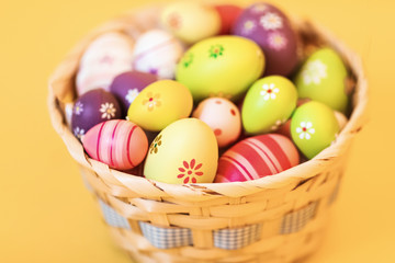 Colorful Easter eggs in a basket on an isolated yellow background
