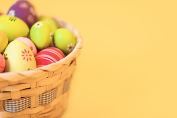 Colorful Easter eggs in a basket on an isolated yellow background