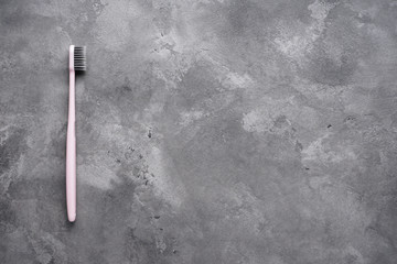 Flat lay composition of a pink toothbrush on a gray background, with space for text