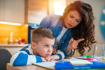 Obraz premium Mother Becoming Frustrated With Son Whilst Doing Homework. Mom makes the best teacher ever. Mother scolds a child for poor schooling and homework at home