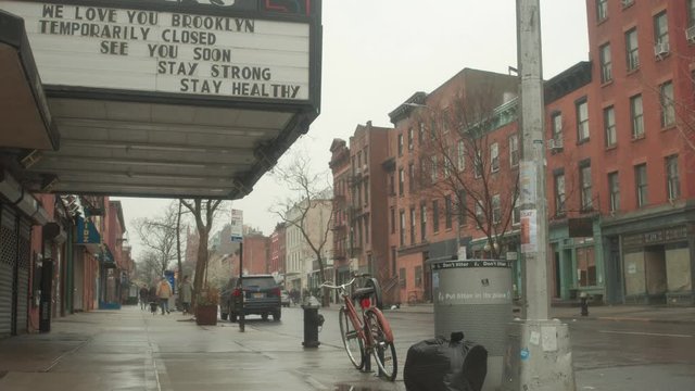 Couple walks under movie theater marquee in Brooklyn during Corona quarantine