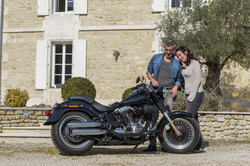 Fototapeta na wymiar husband introduces his new custom motorcycle to his wife