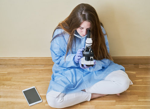 Young Medical Researcher Sitting On The Floor Of A Classroom With A Tablet And Next To It A Laboratory Microscope, Medical Concept And Training