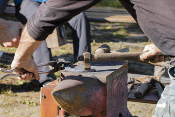 blacksmith beats on the anvil forging a horseshoe