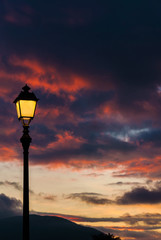 Fototapeta na wymiar Old fashioned street lamp against sunset sky clouds (with copy space)