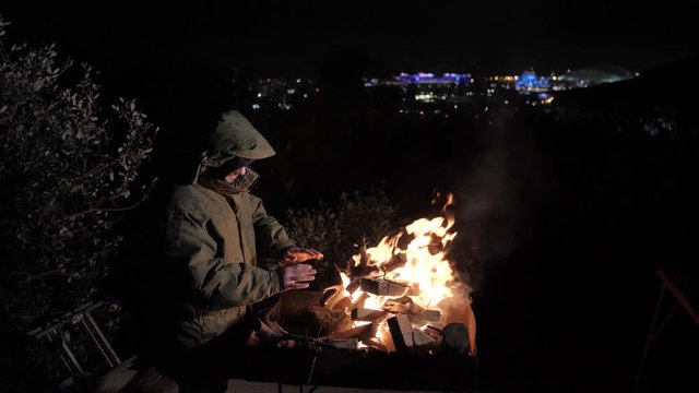 man in military uniform warms up by the fire