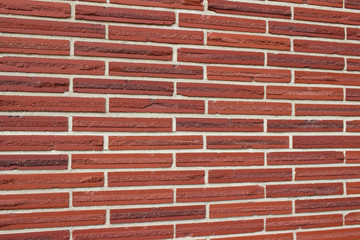 Vintage red color brick wall background with textured striped bricks in a 1/3 offset brickwork pattern (angle view)