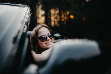 Young woman cabriolet car driver at sunset. Riding a journey driving.