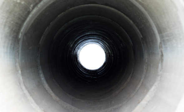 The tunnel cement pipe has black shadow and light at the end of the tunnel.