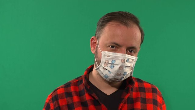 Close Up Of a Man With A Medical Mask Filmed On Chroma Key. Man Wearing Hygienic Mask. Coronavirus Protection Covid - 19. Portrait Of Medical Doctor Putting Mask On Green Background. 4K video