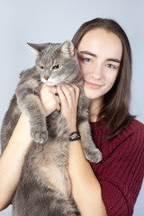 Beautiful smiling brunette holds in her arms a large striped gray cat