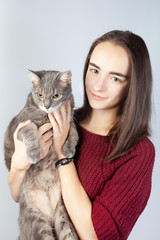 Beautiful smiling brunette holds in her arms a large striped gray cat