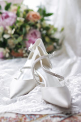 Obraz na płótnie Canvas Bride's wedding white shoes with flowers on the back close up