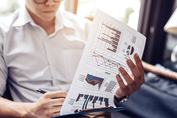 Businessman hold pen and working calculate data. document graph chart and report marketing. Business office concept.