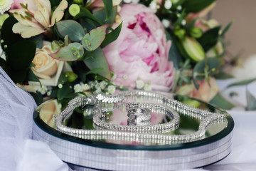 Obraz na płótnie Canvas Bride's wedding jewellery and flowers on a glass surface close up