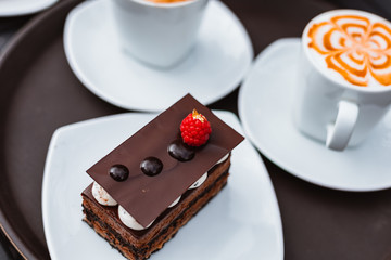 Slice of chocolate cake, Cutlery steak basket and donot with coffee on the table.